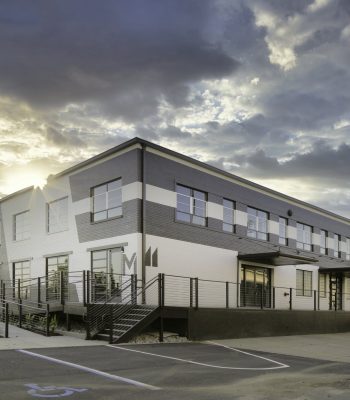 A Large Building With A Clock On The Side Of A Road